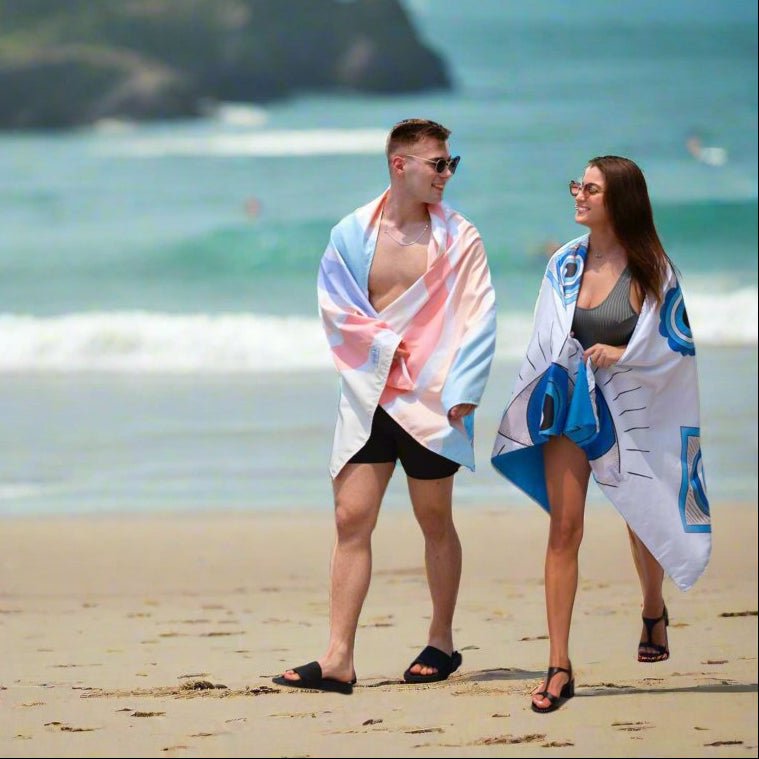 Guy and girl walking on the beach covered with beach towels from la toalla