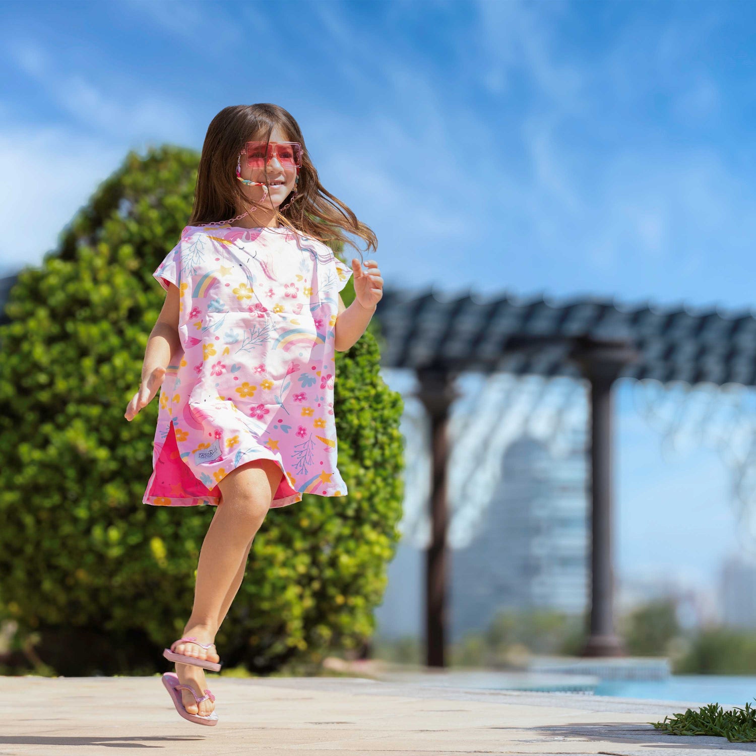 Little girl wearing a La Toalla Beach poncho and running happily