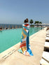 Person wrapped in a colorful towel by a pool with ocean view